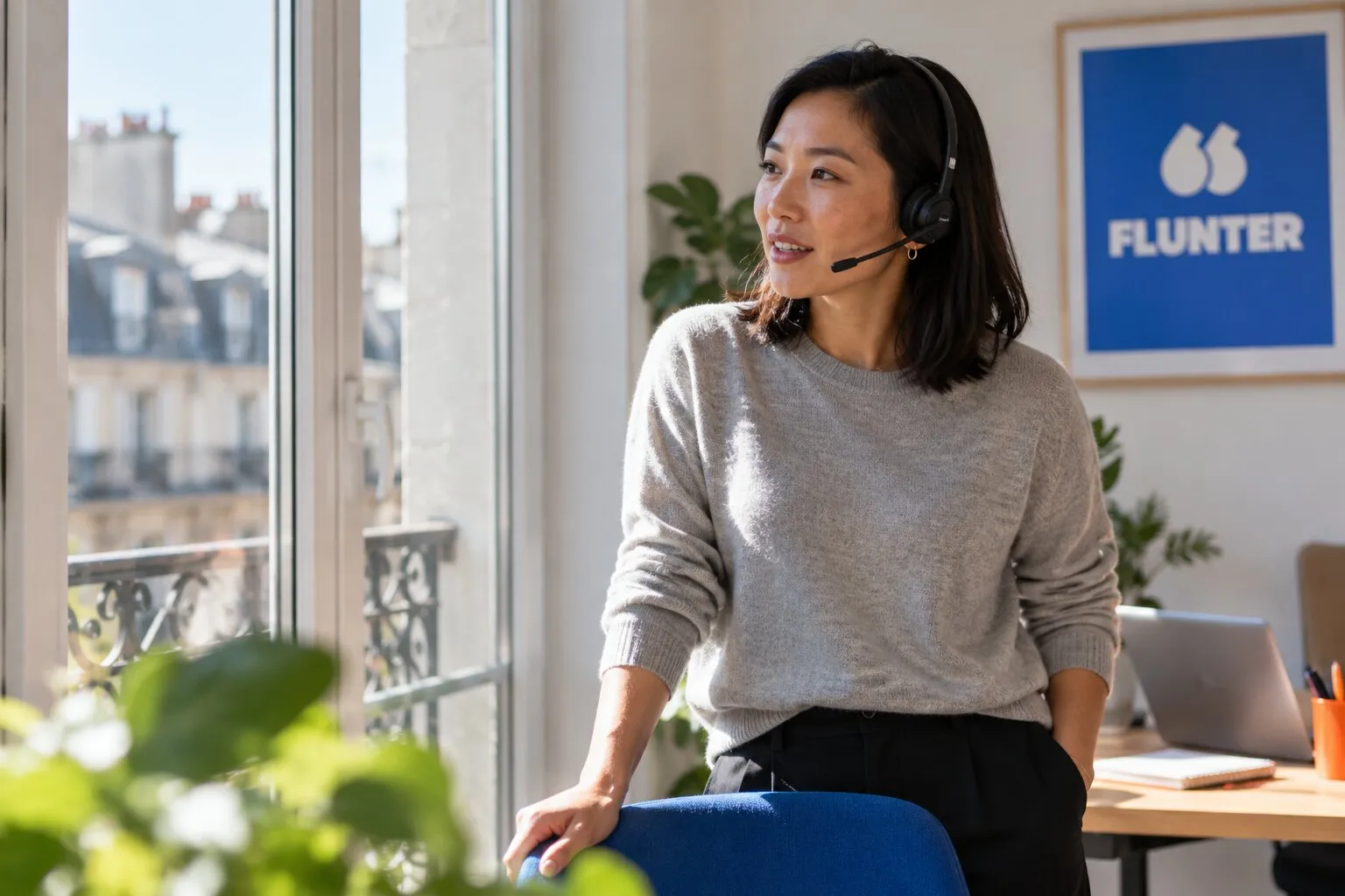 Sales rep with a headset on a call by a window, Flunter poster on the wall