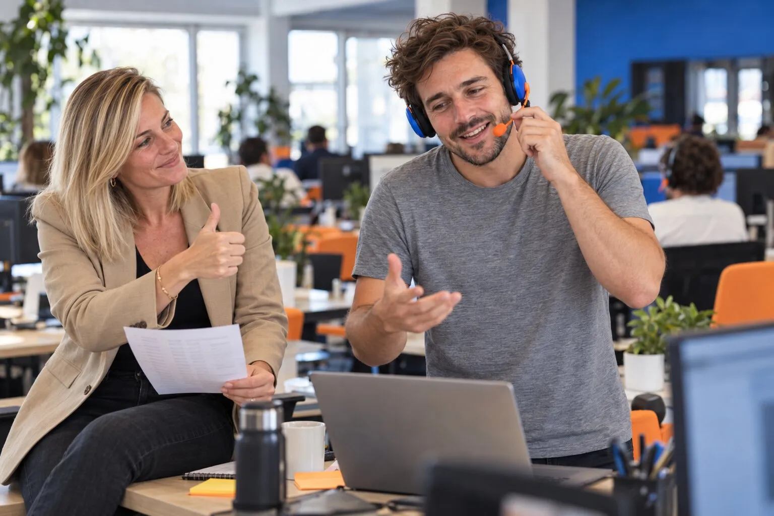 Un commercial au casque en plein appel, sa team lead lève le pouce, liste de prospects en main