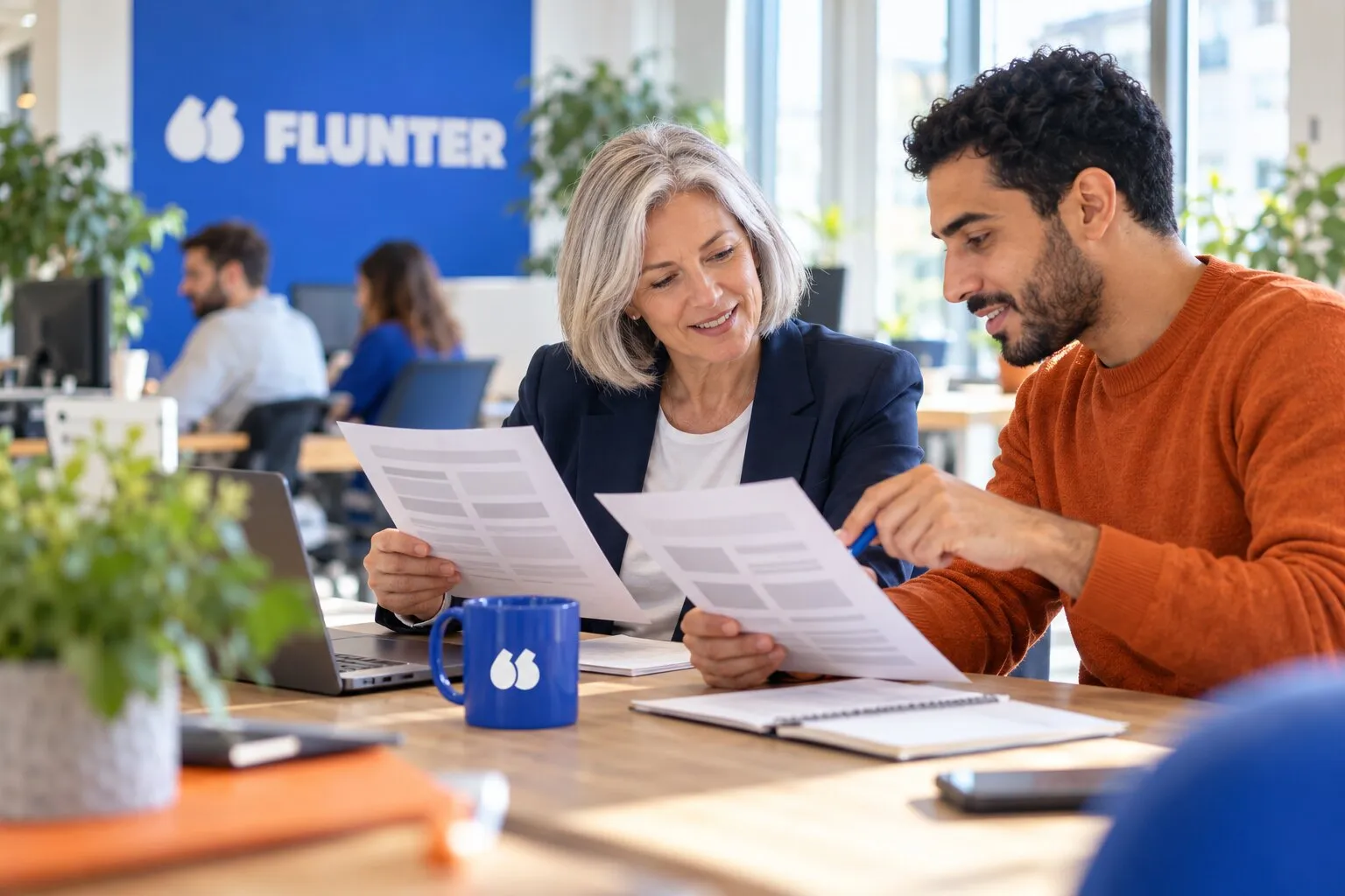 Deux collègues comparent deux offres de logiciel imprimées avant de choisir leur outil