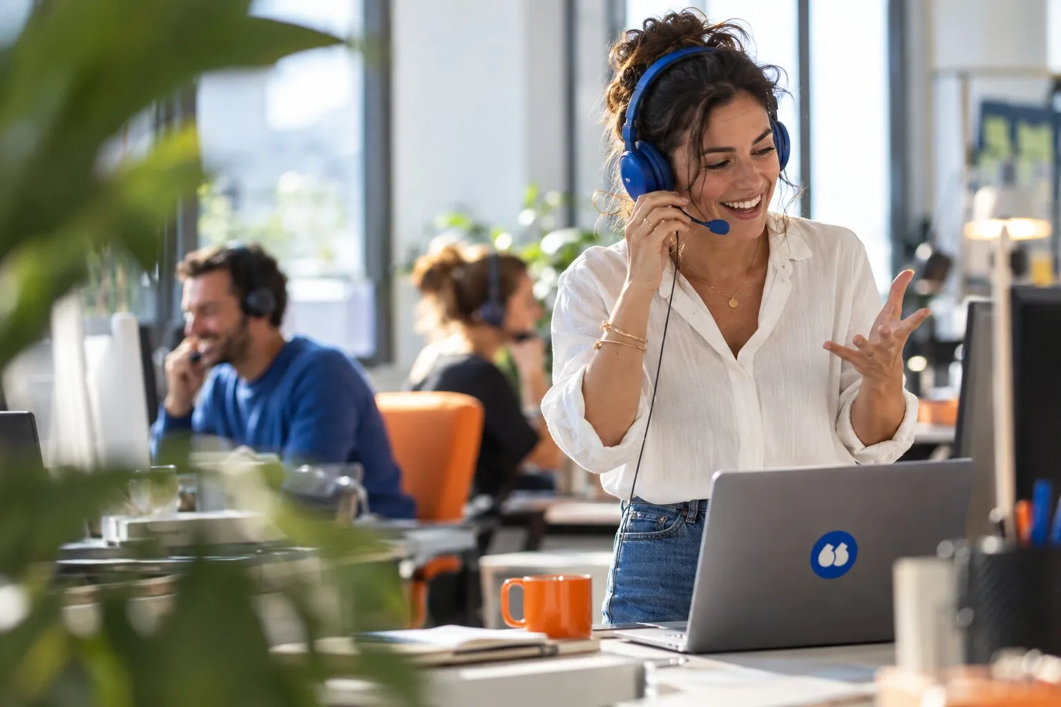 Une commerciale au casque bleu, souriante, en pleine conversation avec un prospect